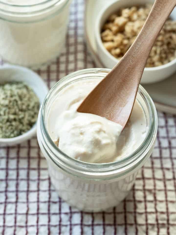 a small wooden spoon scooping up vegan tofu yogurt from a jar.
