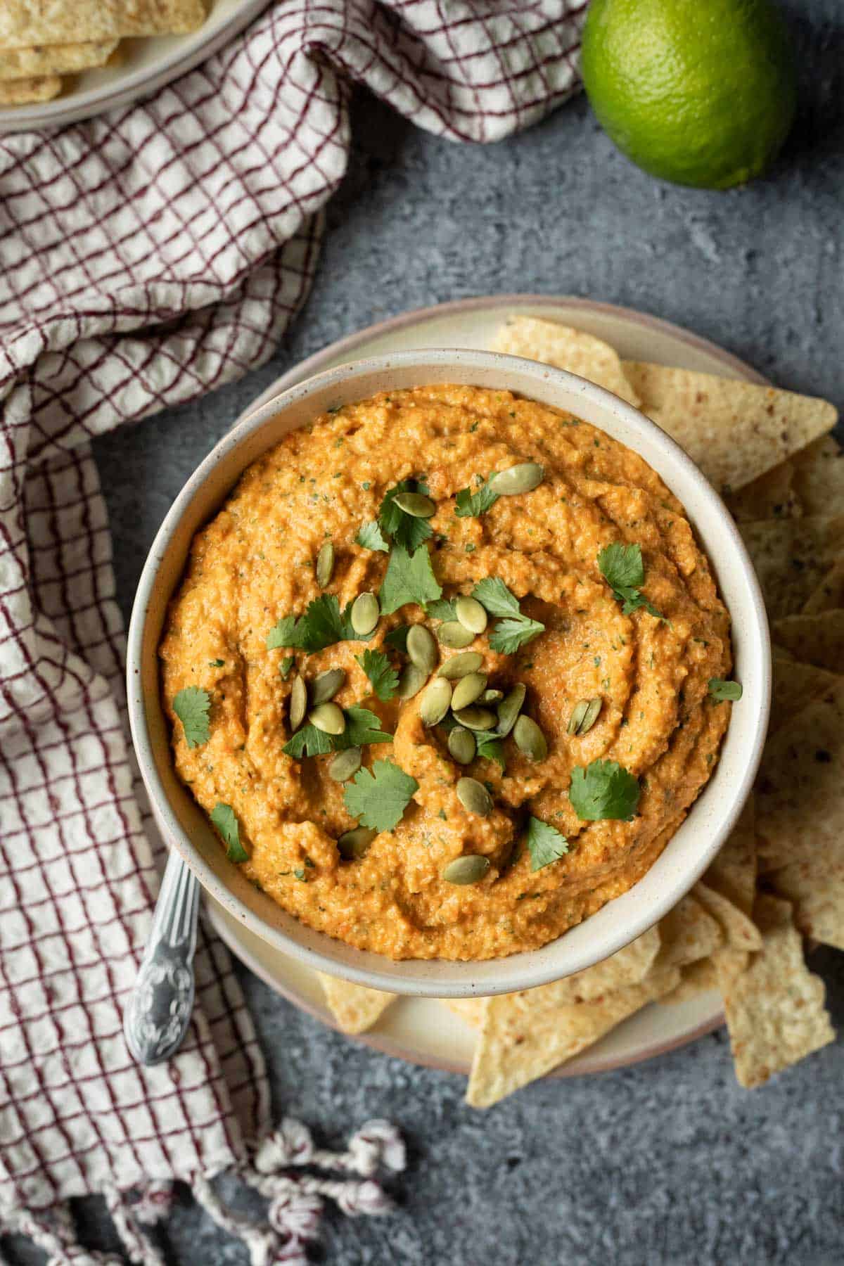 A bowl of buffalo cauliflower dip surrounded by tortilla chips.