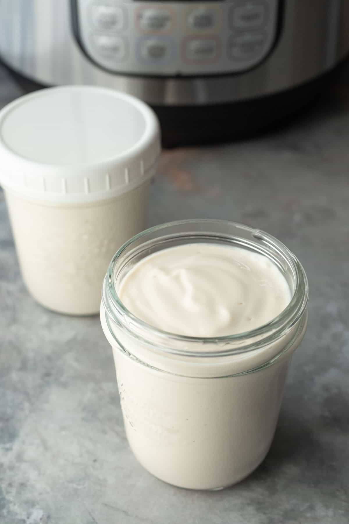 Two small glass jars filled with tofu yogurt with an Instant Pot in the background.