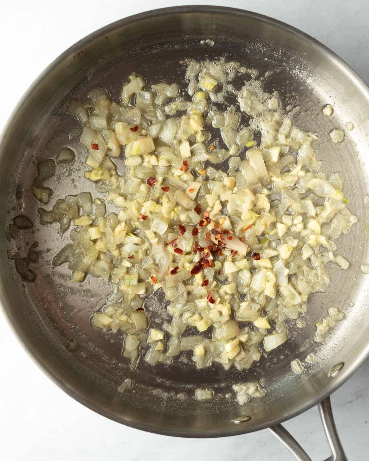 Sauteing shallot, garlic, and red pepper flakes in butter and oil.