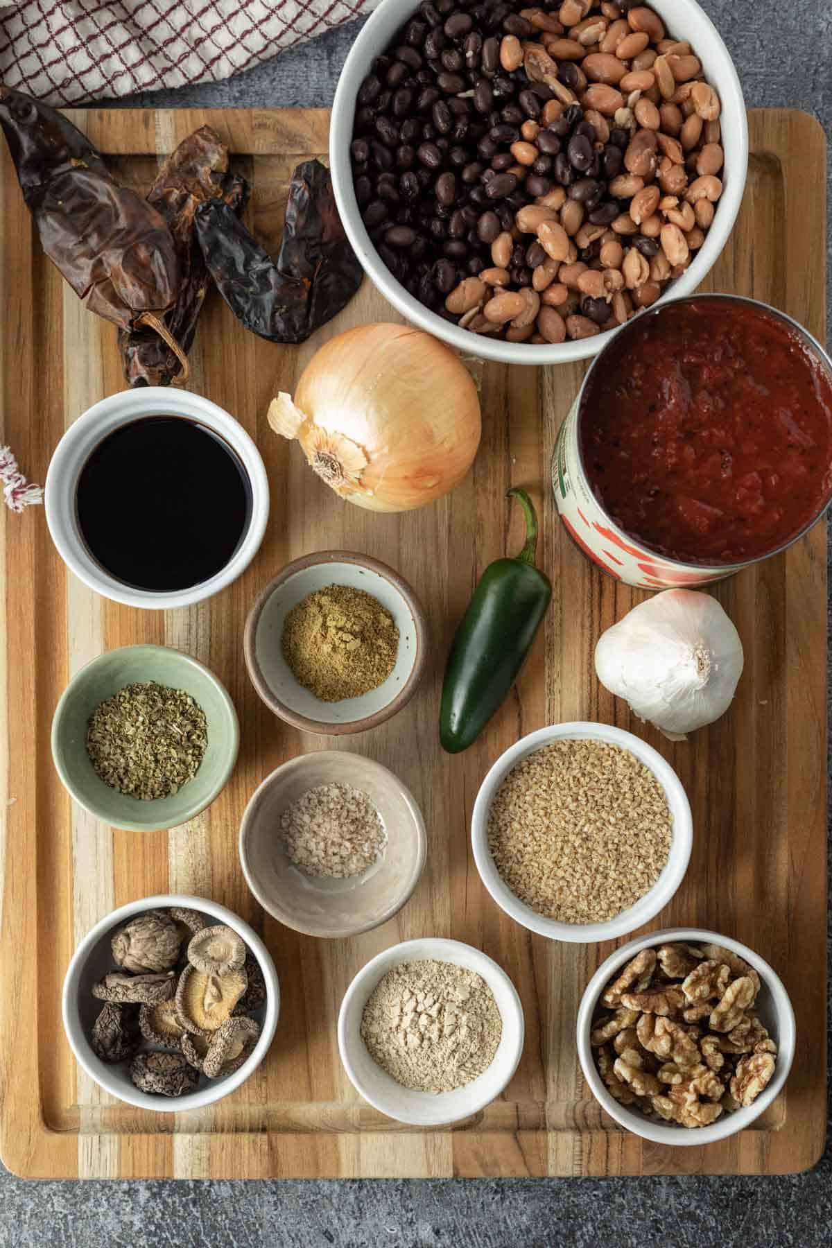 all ingredients needed for this chili recipe laid out on a large wood cutting board.
