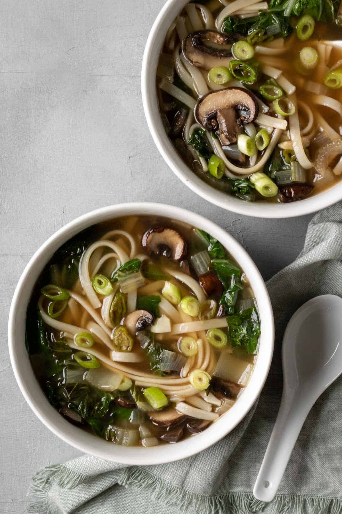 Two bowls of miso soup with noodles and mushrooms.