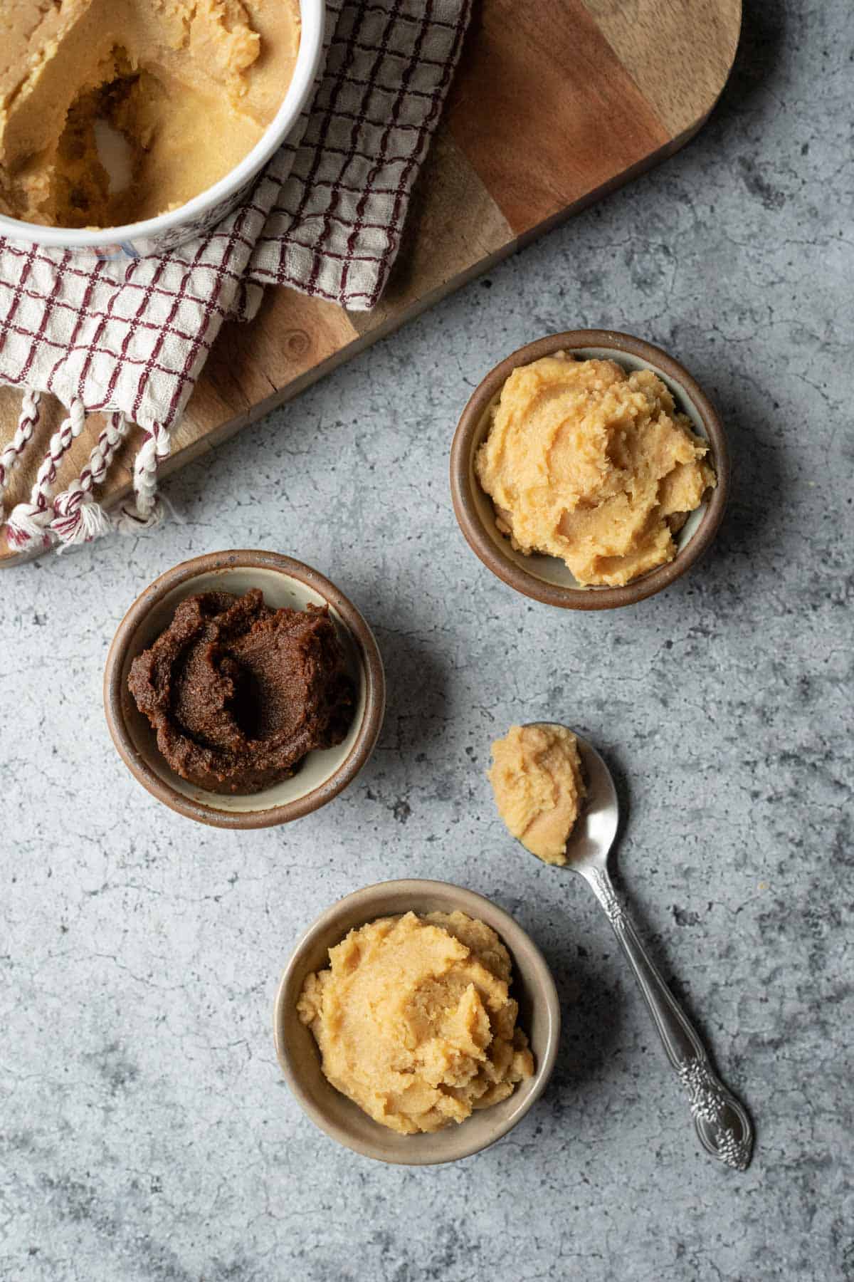 overhead view of white miso, red miso, and chickpea miso in small bowls.