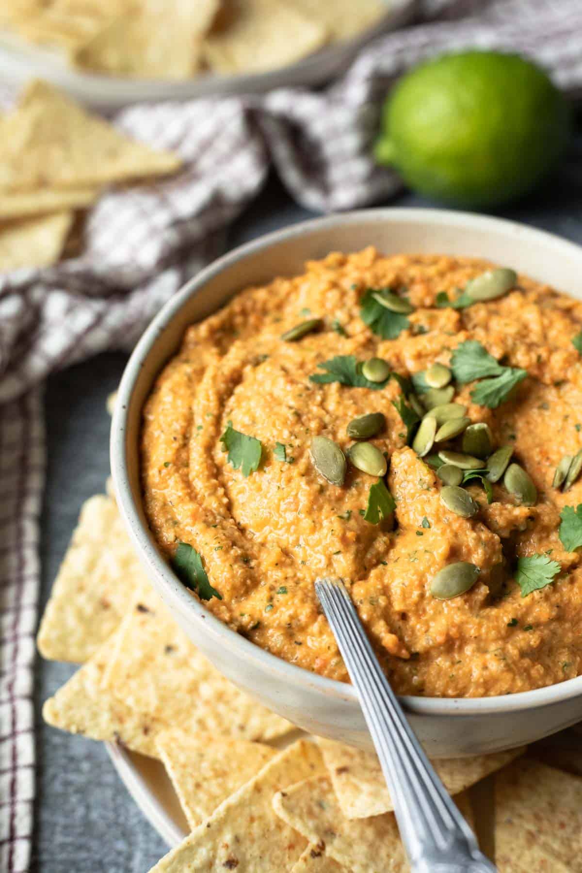 Large bowl filled with creamy buffalo cauliflower dip with a spoon scooping up a serving.