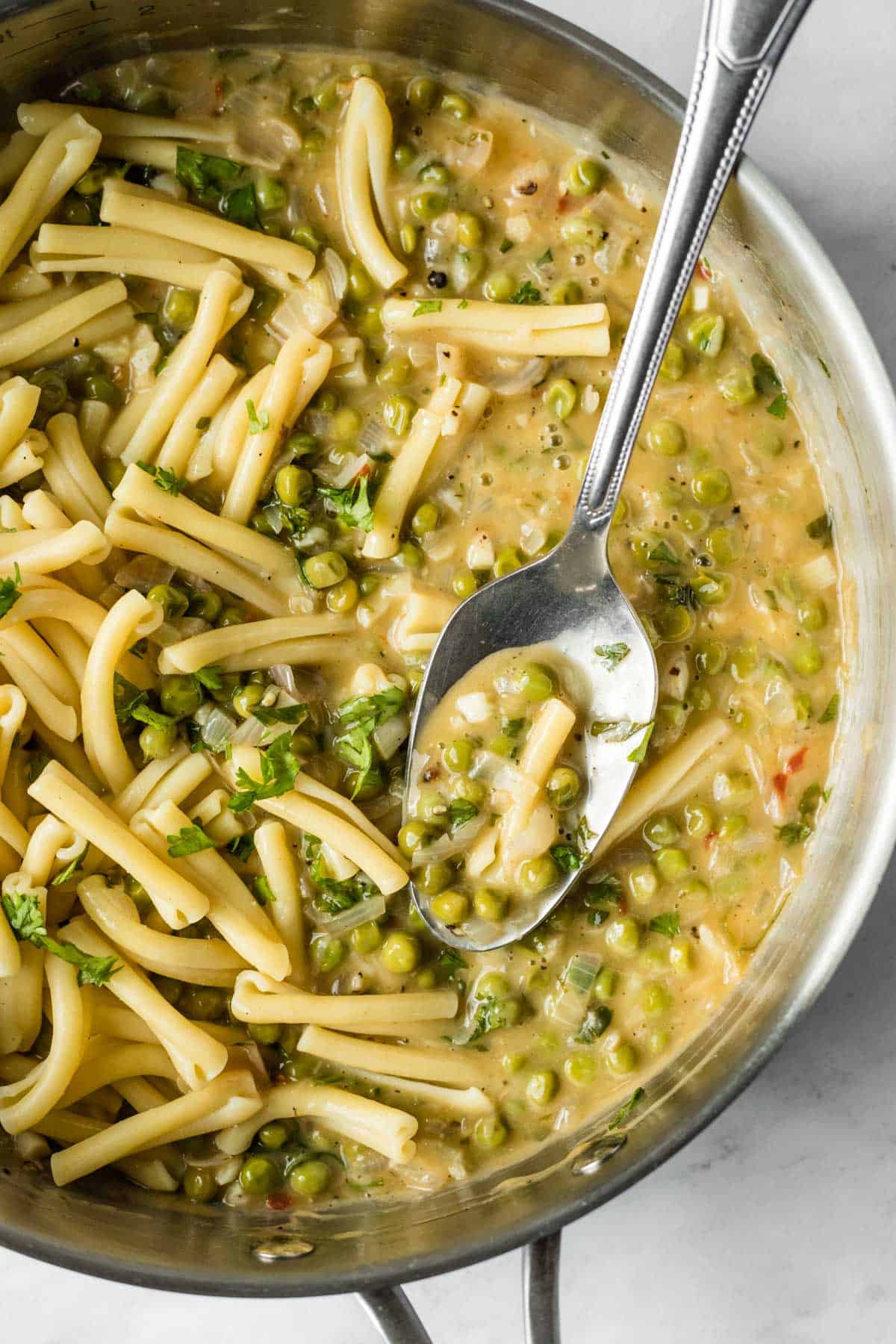 casarecce pasta and peas being tossed with white wine sauce in a large pan.