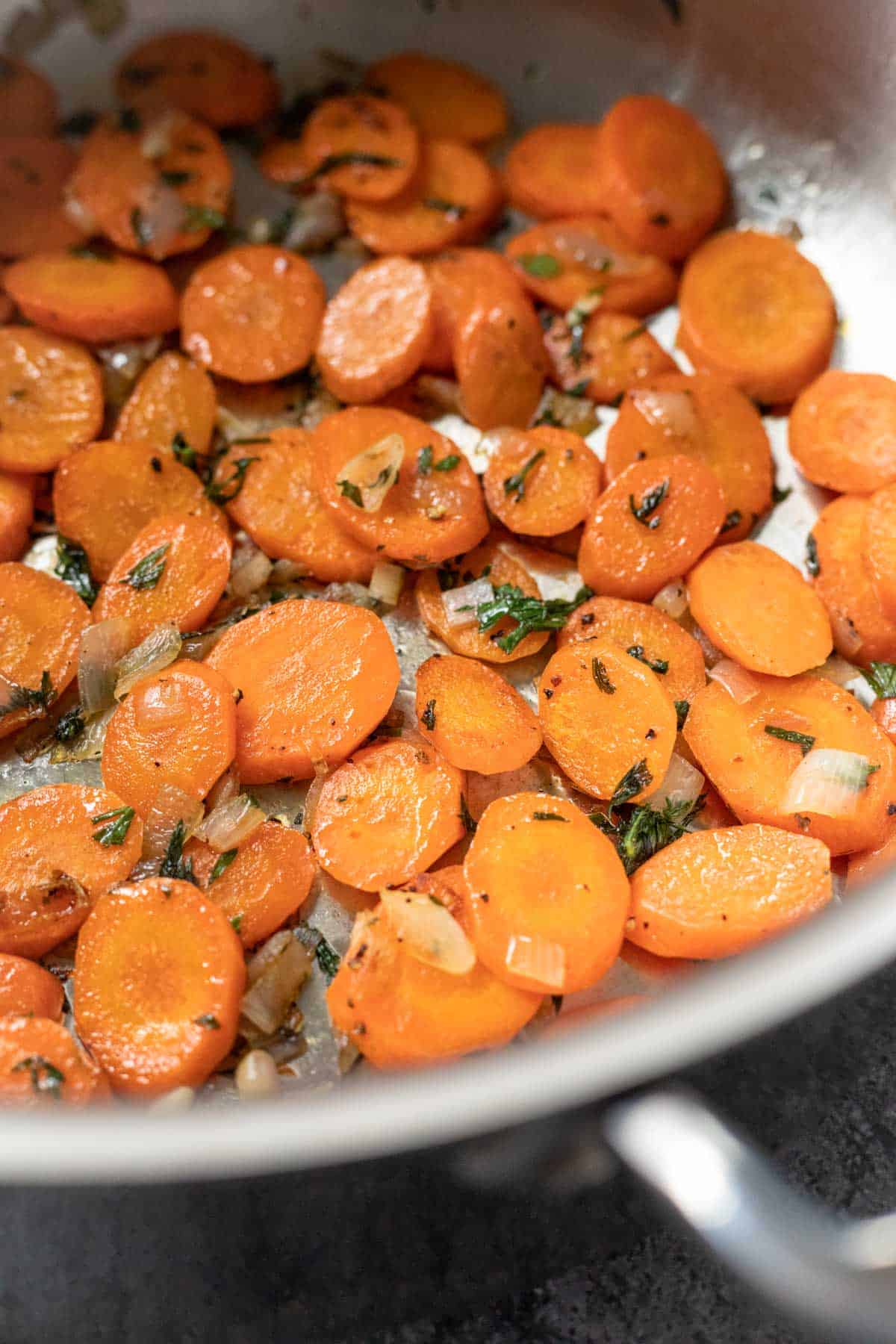close up side view of perfectly sauteed carrots in a pan.