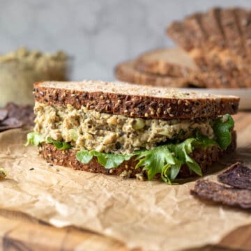 a vegan egg salad sandwich on a cutting board.