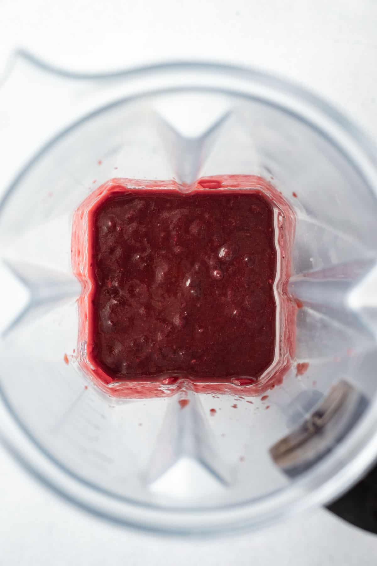 looking inside a blender jar at the blueberry colored bbq sauce.