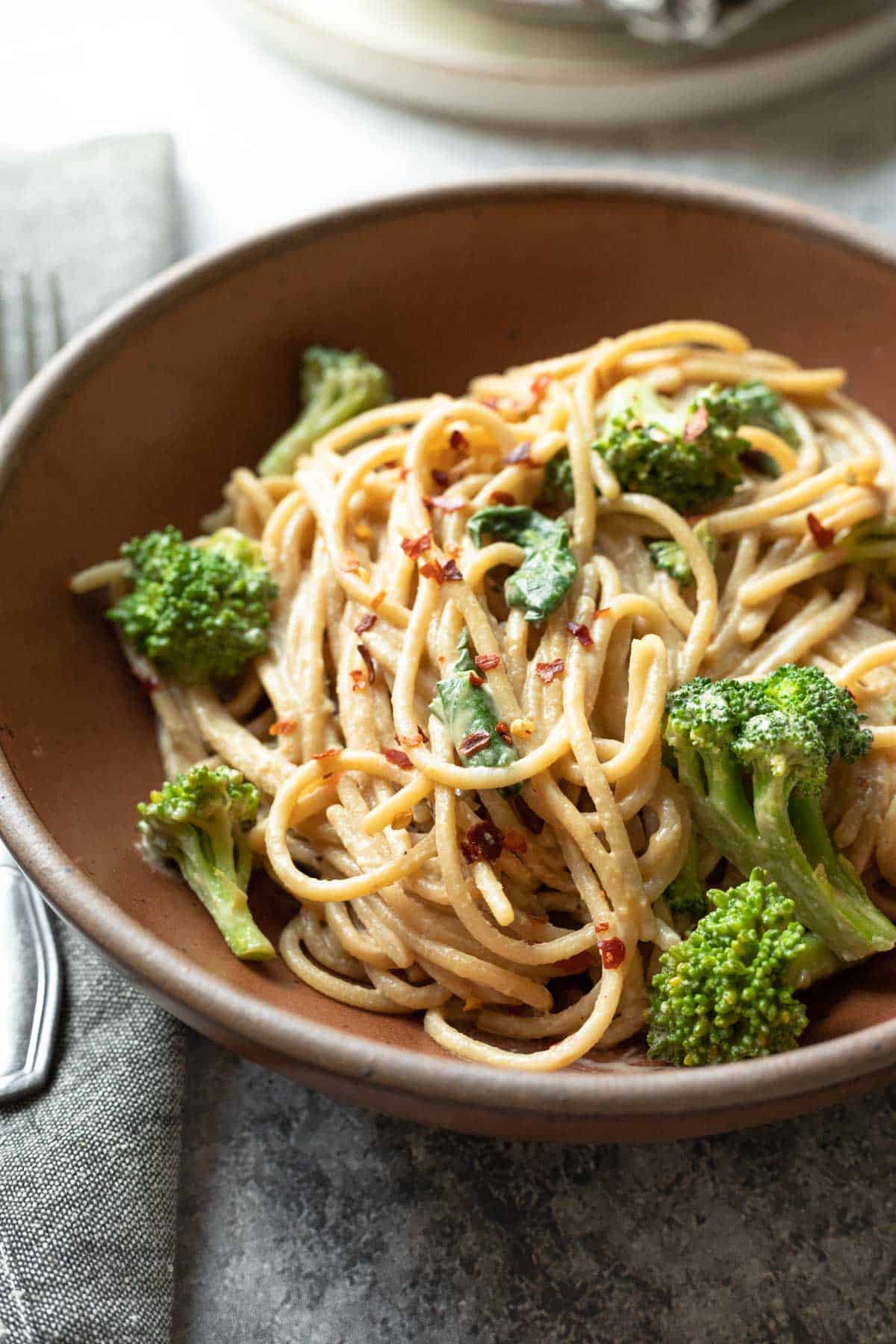 Backlit view of a bowl of tahini noodles with broccoli and bok choy.