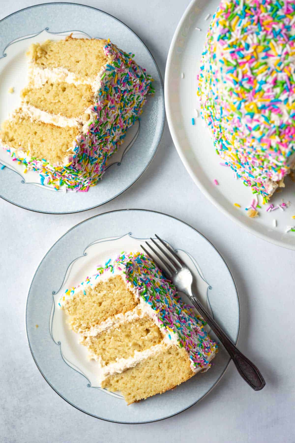 Two slices of vanilla sprinkle cake on plates.