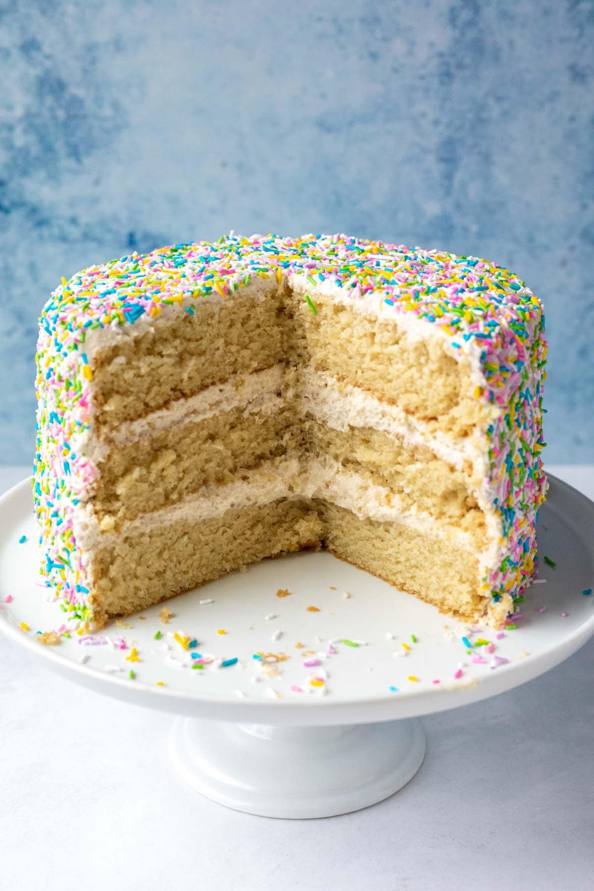 Slices removed from vegan layer cake showing the fluffy vanilla cake and frosting inside.