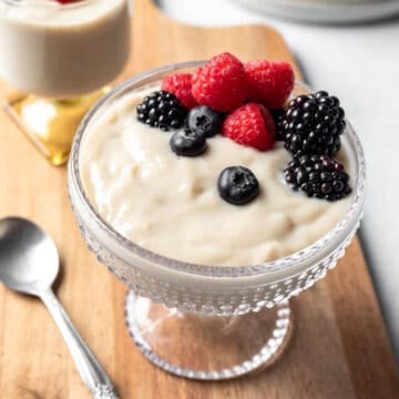 Creamy vanilla pudding in a glass serving dish topped with berries.