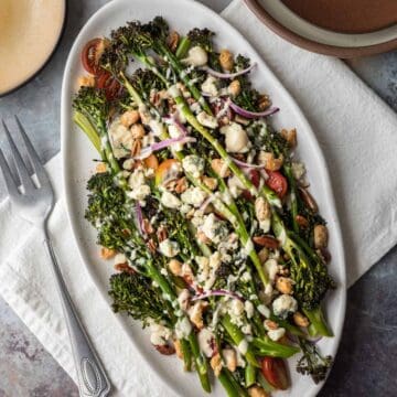 Roasted broccolini salad with blue cheese and creamy dressing on a serving platter.