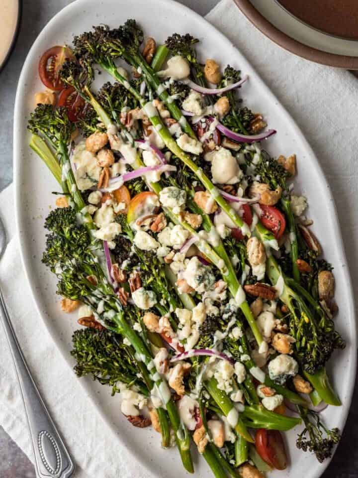 Roasted broccolini salad with blue cheese and creamy dressing on a serving platter.