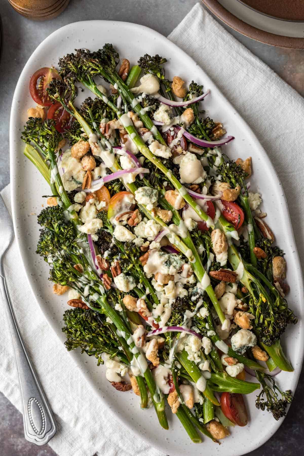 Broccolini salad with vegan blue cheese and tahini dressing on a serving platter.
