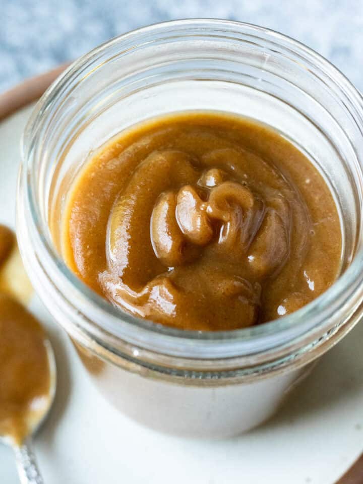 Golden brown date caramel in a glass jar.