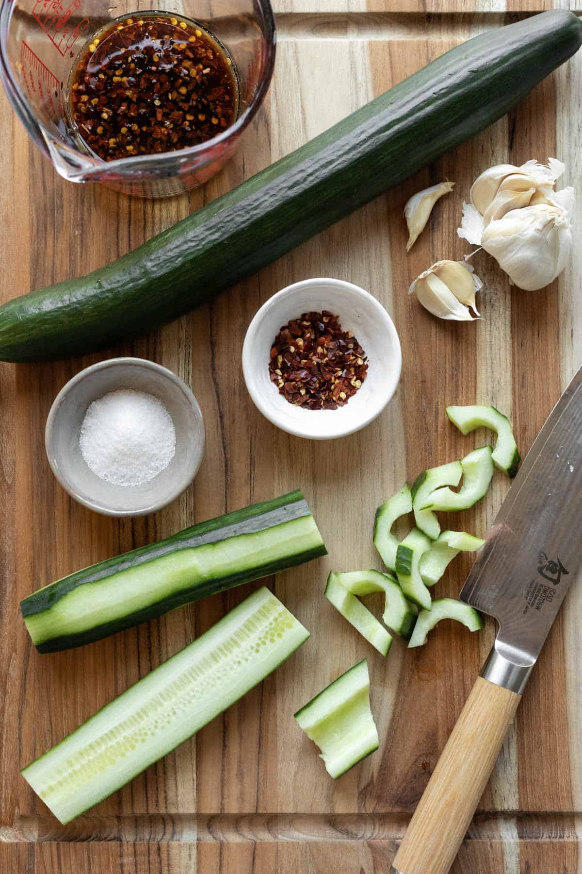 Slicing cucumbers for stir fry and other ingredients laid out on a wood cutting board.