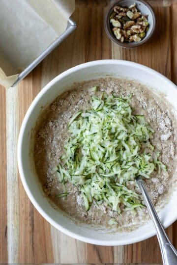 Folding grated zucchini into the batter.