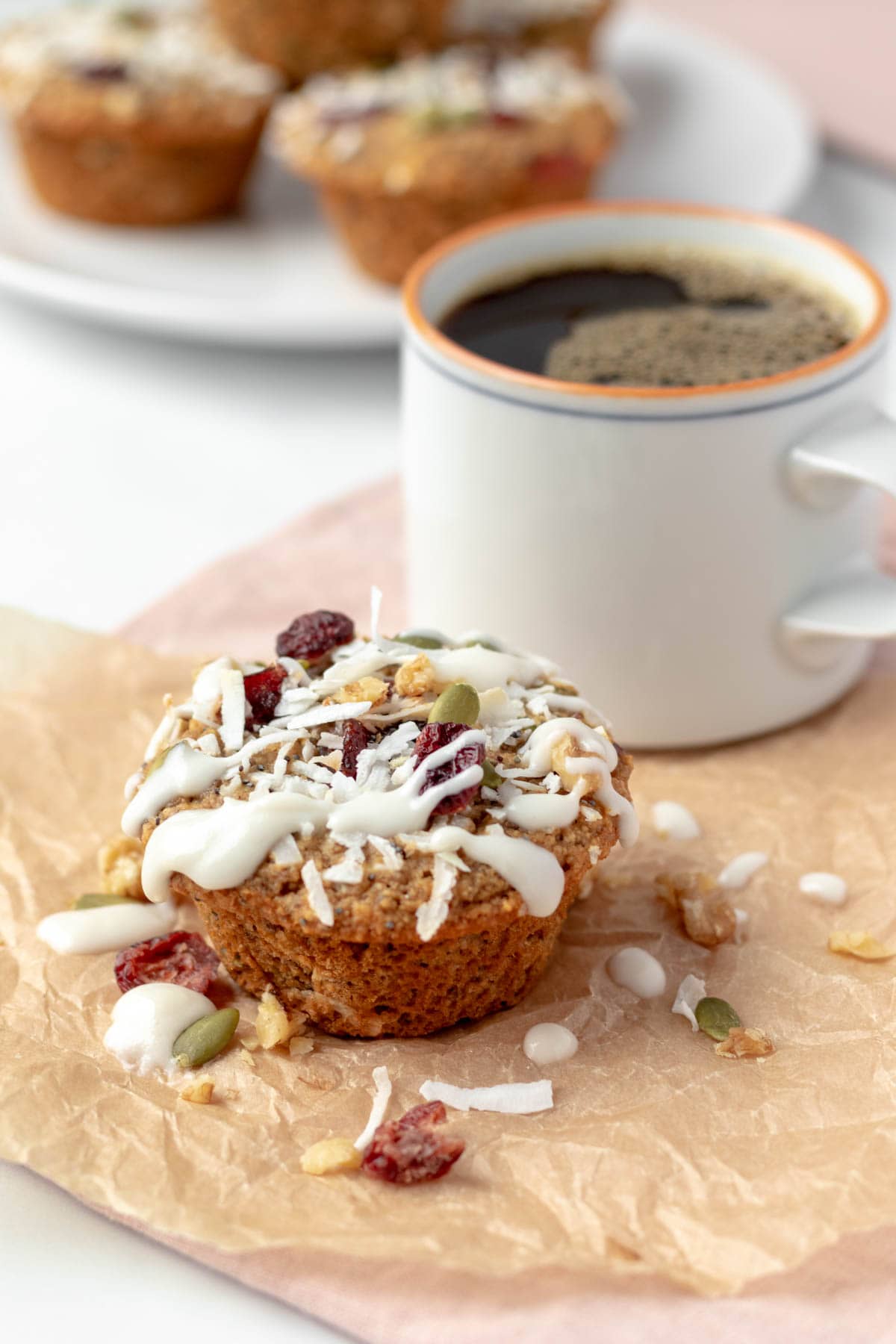 A decorated muffin on parchment paper next to a mug of coffee.