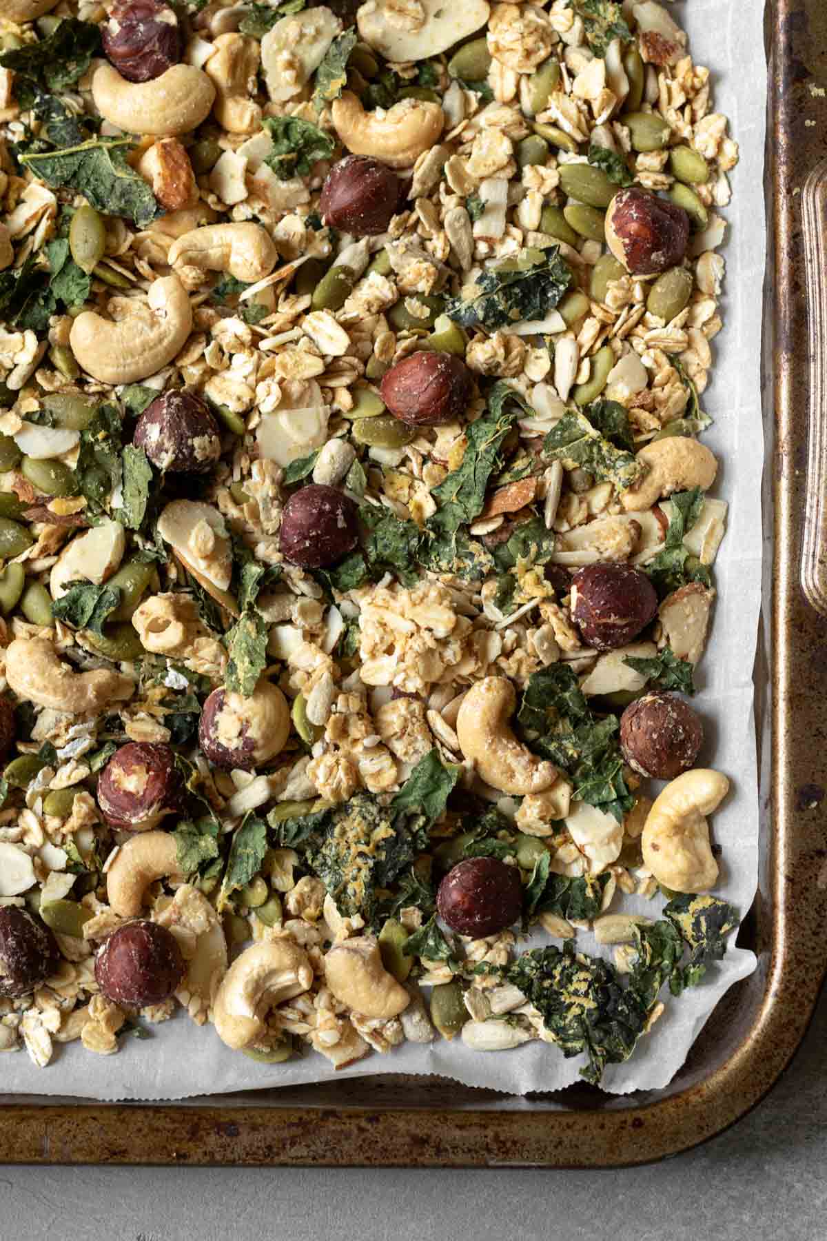 Savory Granola with cashews and kale spread on a baking sheet.
