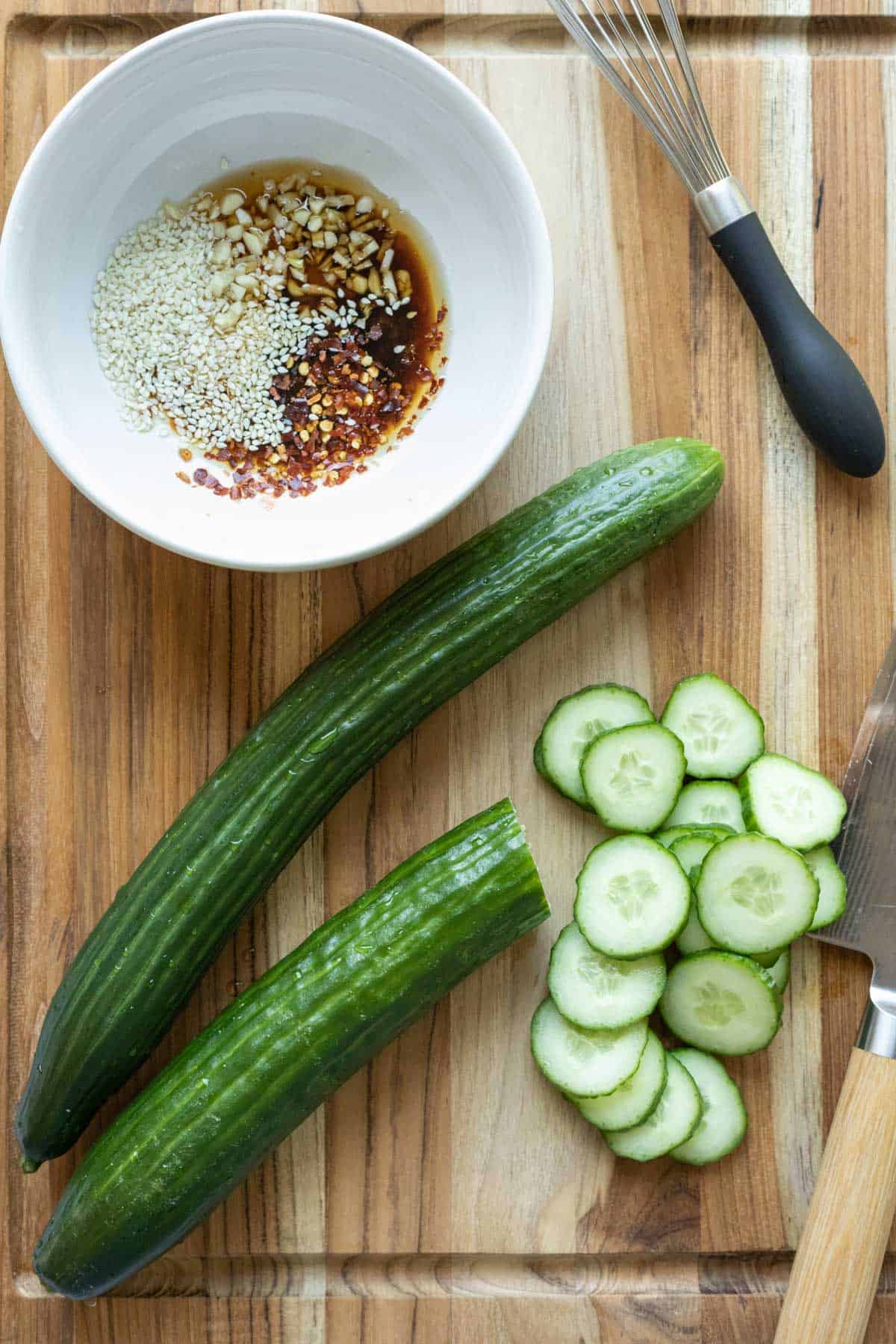 Slicing hot house cucumbers and mixing spicy Asian dressing in a bowl.
