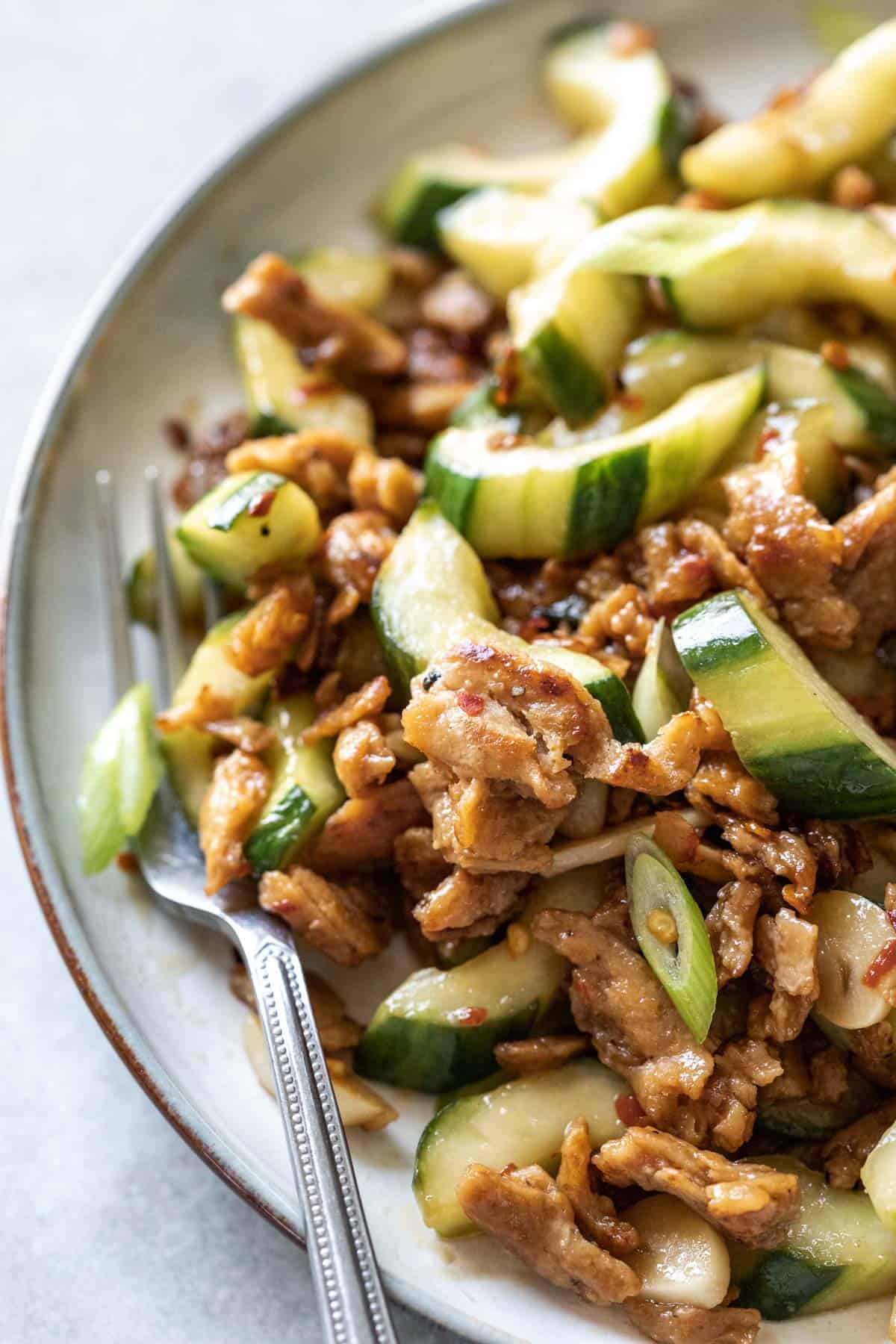 Side view of a plate of cucumber and mock pork stir fry.