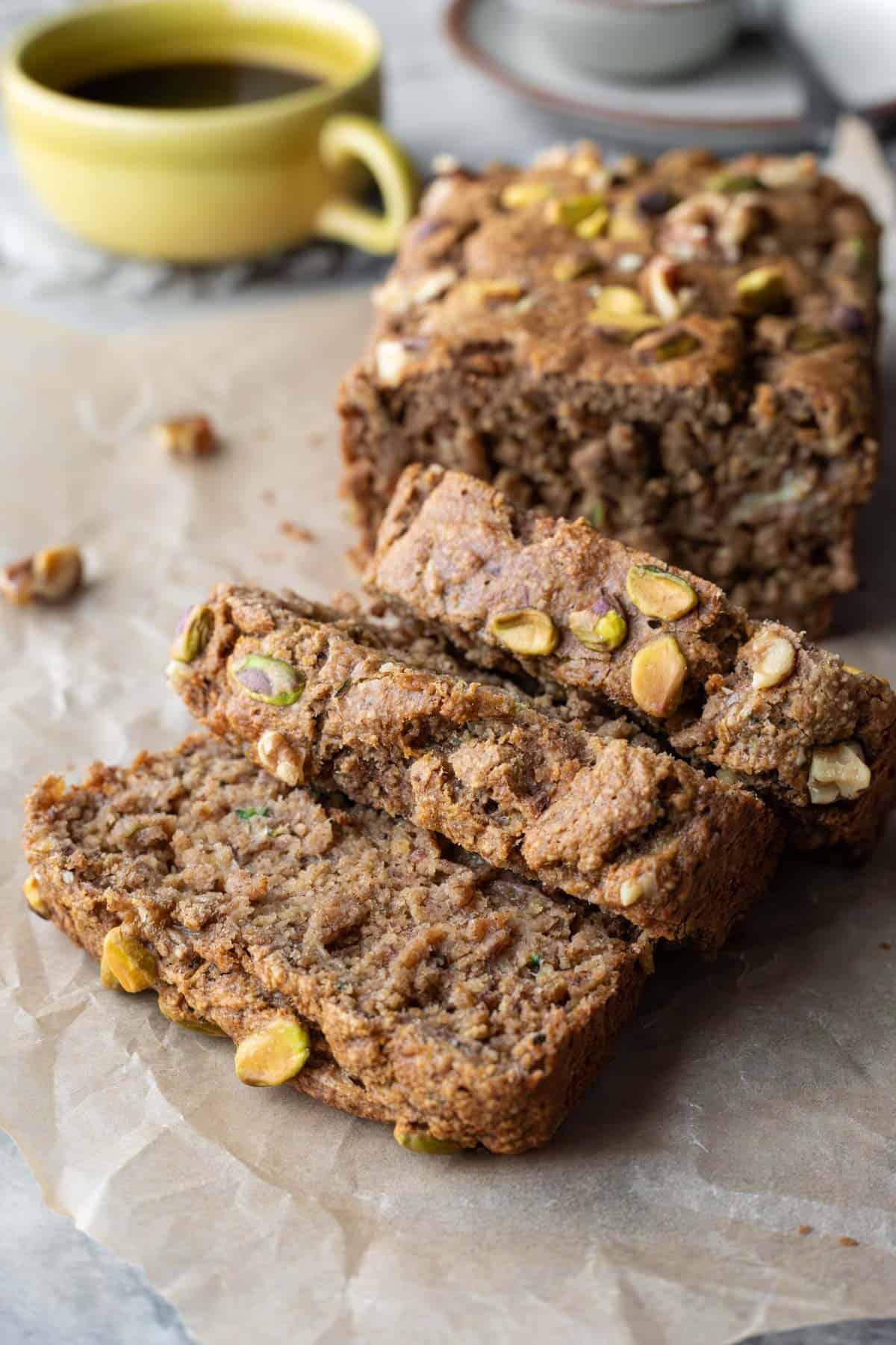 Three slices cut from a loaf of zucchini banana bread resting on parchment paper.