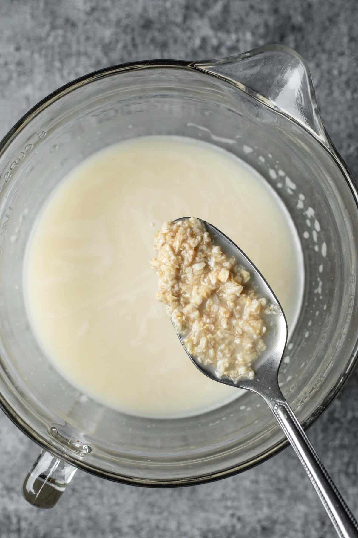 Spooning up oats that have soaked in enzymes and water showing how soft and broken down they get.