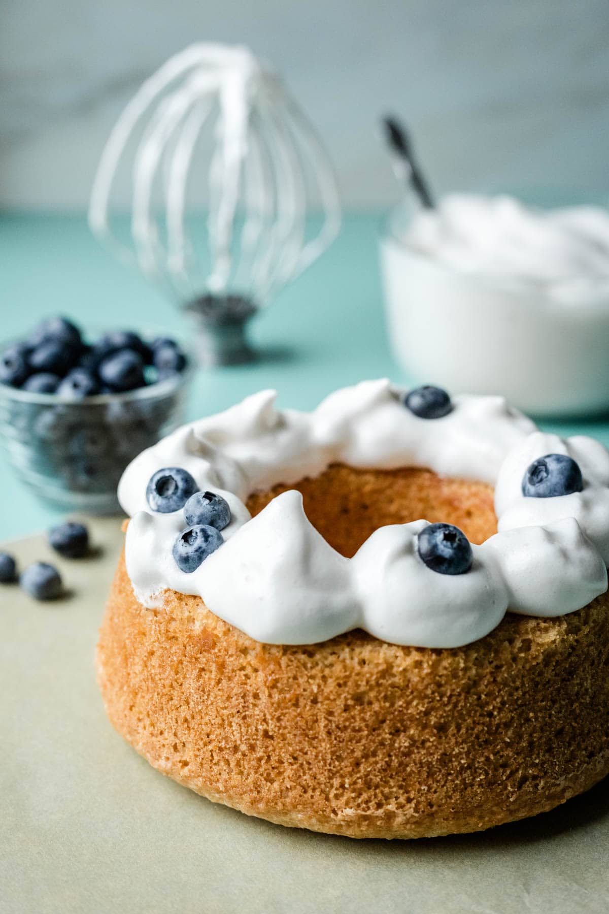 Vegan whipped cream dolloped on top of angel food cake with blueberries.