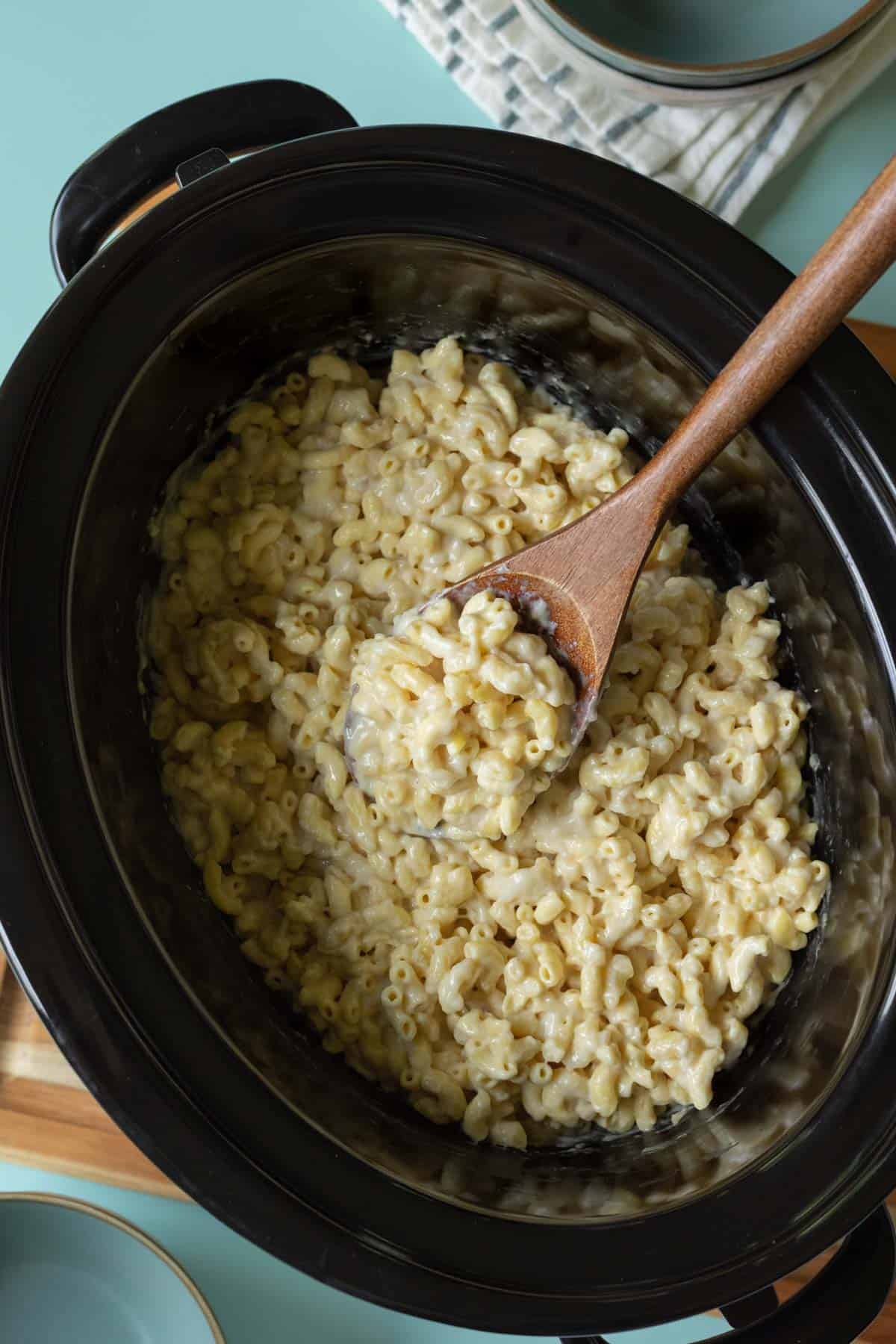 Scooping up vegan mac and cheese from a slow cooker.