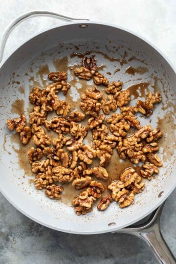 Cooking walnuts, maple syrup, and spices in a large saute pan.