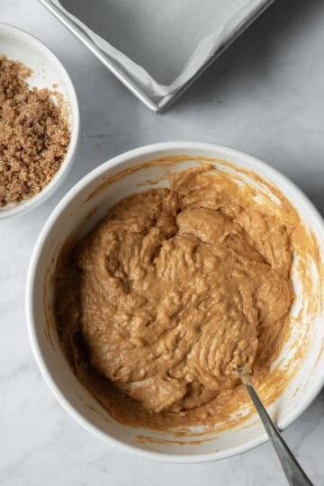 Stirring together the thick pumpkin cake batter in a large mixing bowl.