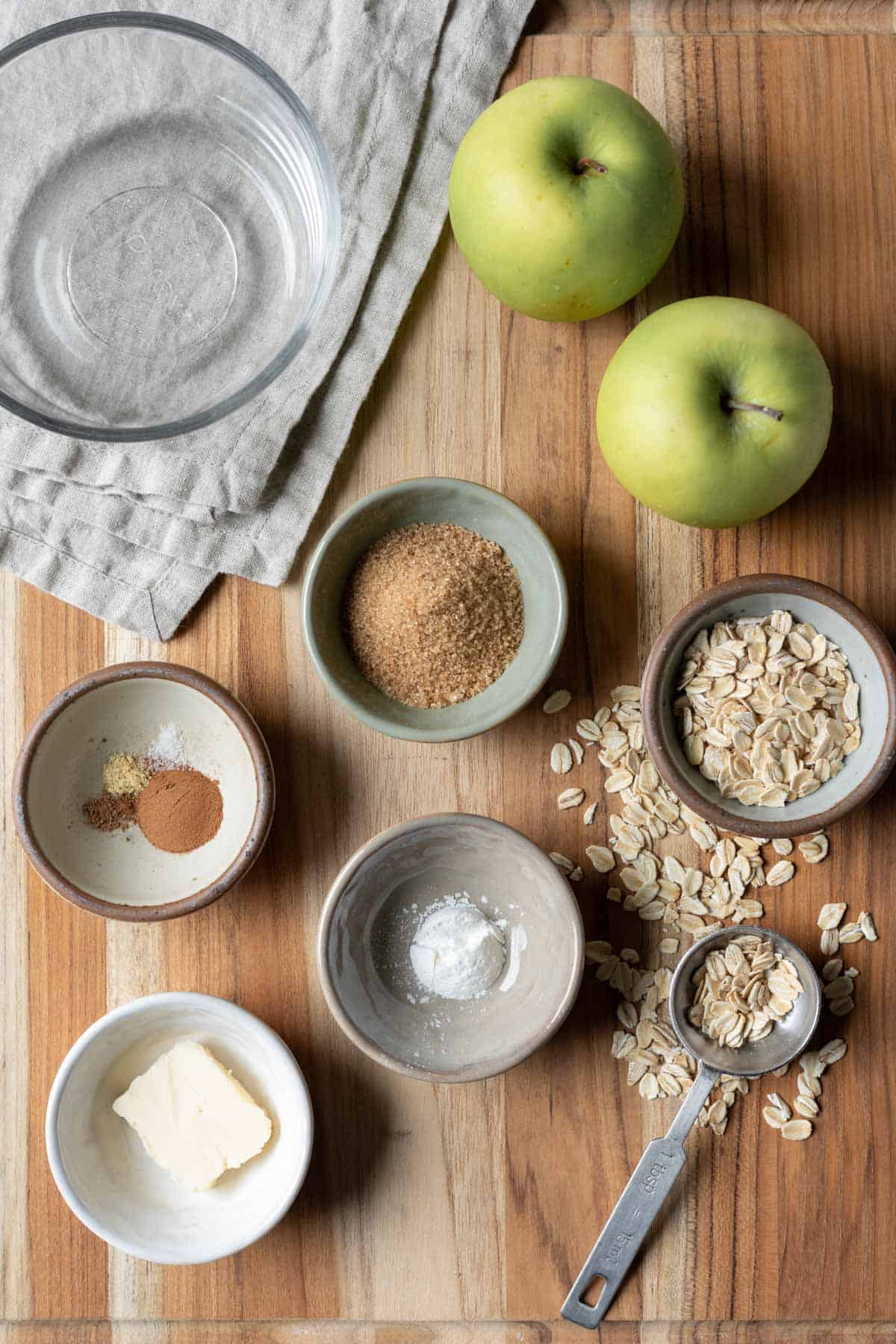 Ingredients for vegan mug apple crisp laid out on a wood board.