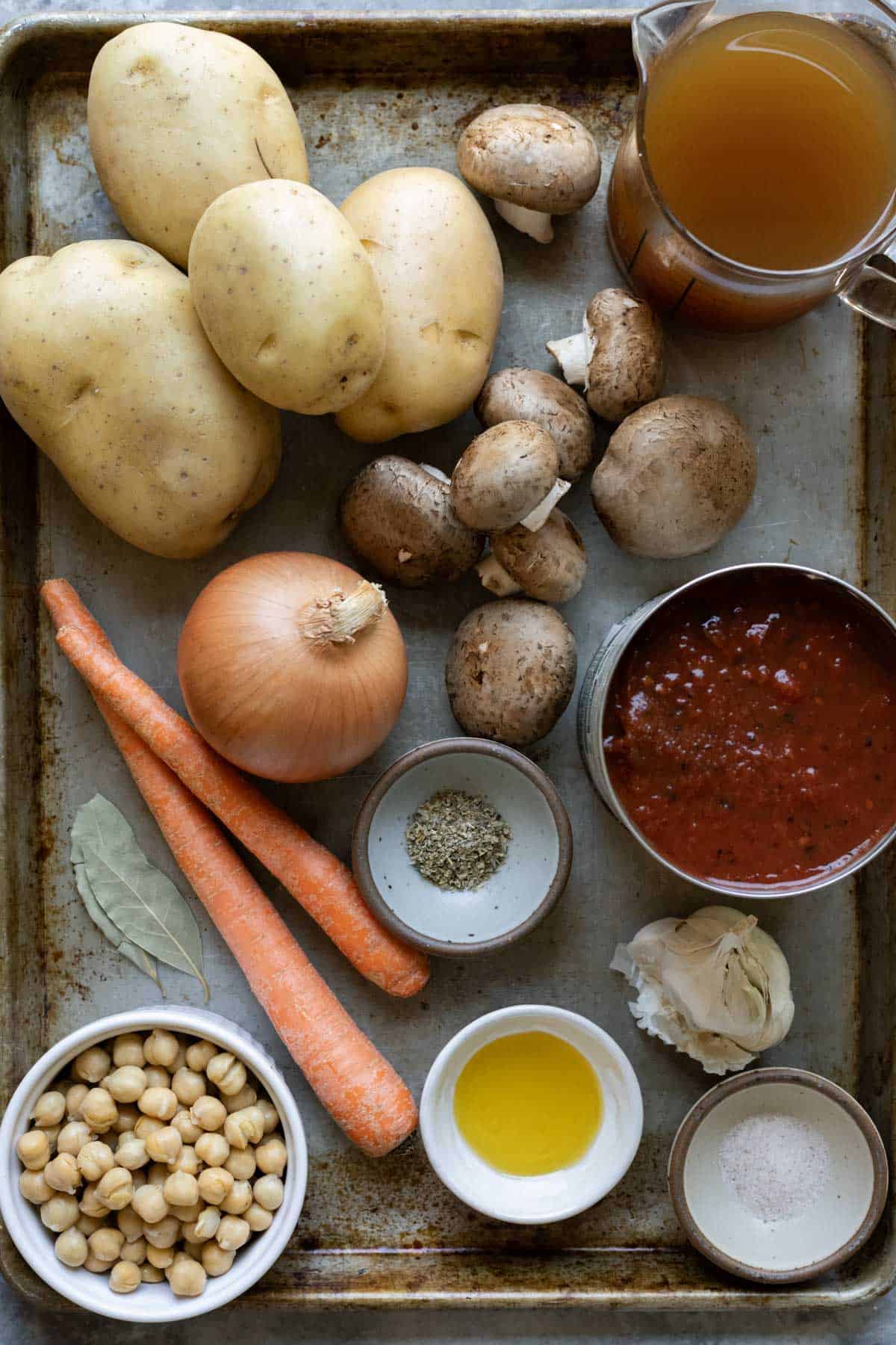 The 11 ingredients needed for potato stew spread out on a large pan.