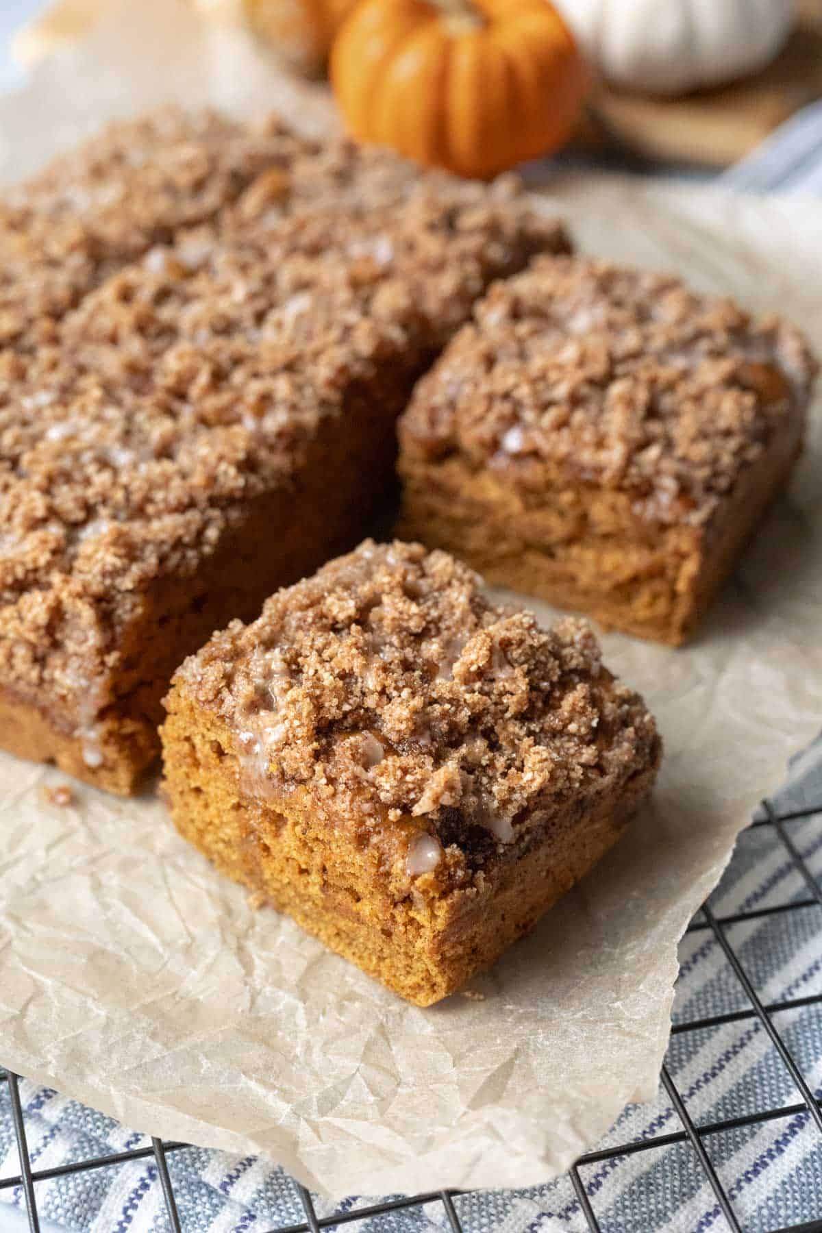 Pumpkin coffee cake cut into 9 squares resting on parchment paper.