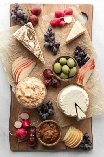 Arranging grapes and sliced apple and pear on the board.