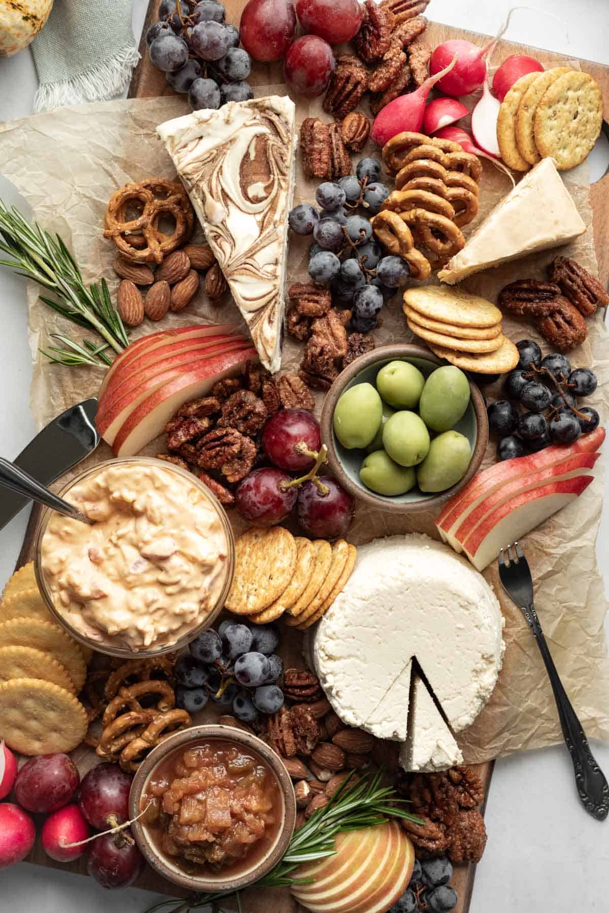 Close up overhead view of a colorful vegan cheese board complete with fruits, candied nuts, dips and crackers.
