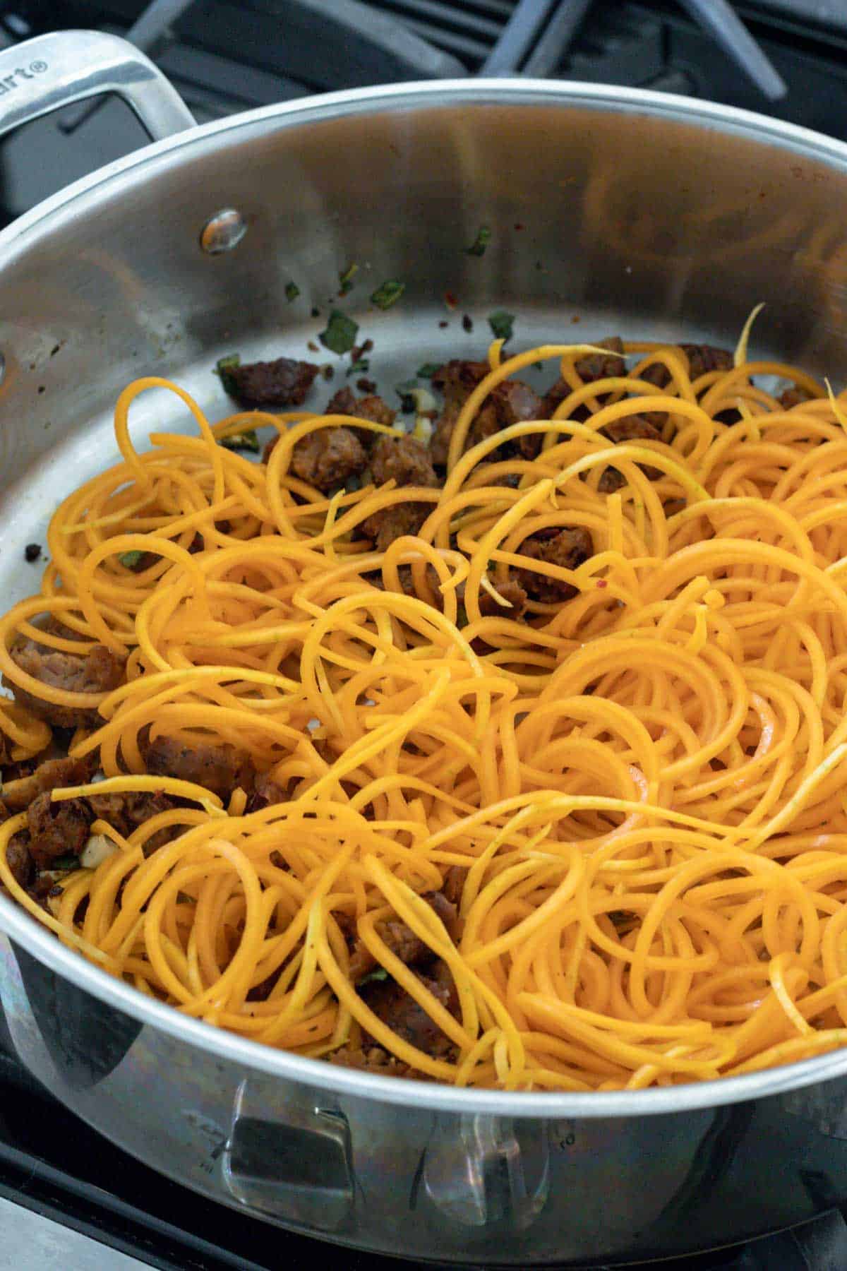 Sausage and spiralized butternut squash in a large saute pan.