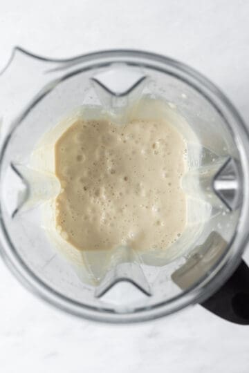 Looking inside a blender at the creamy sauce.