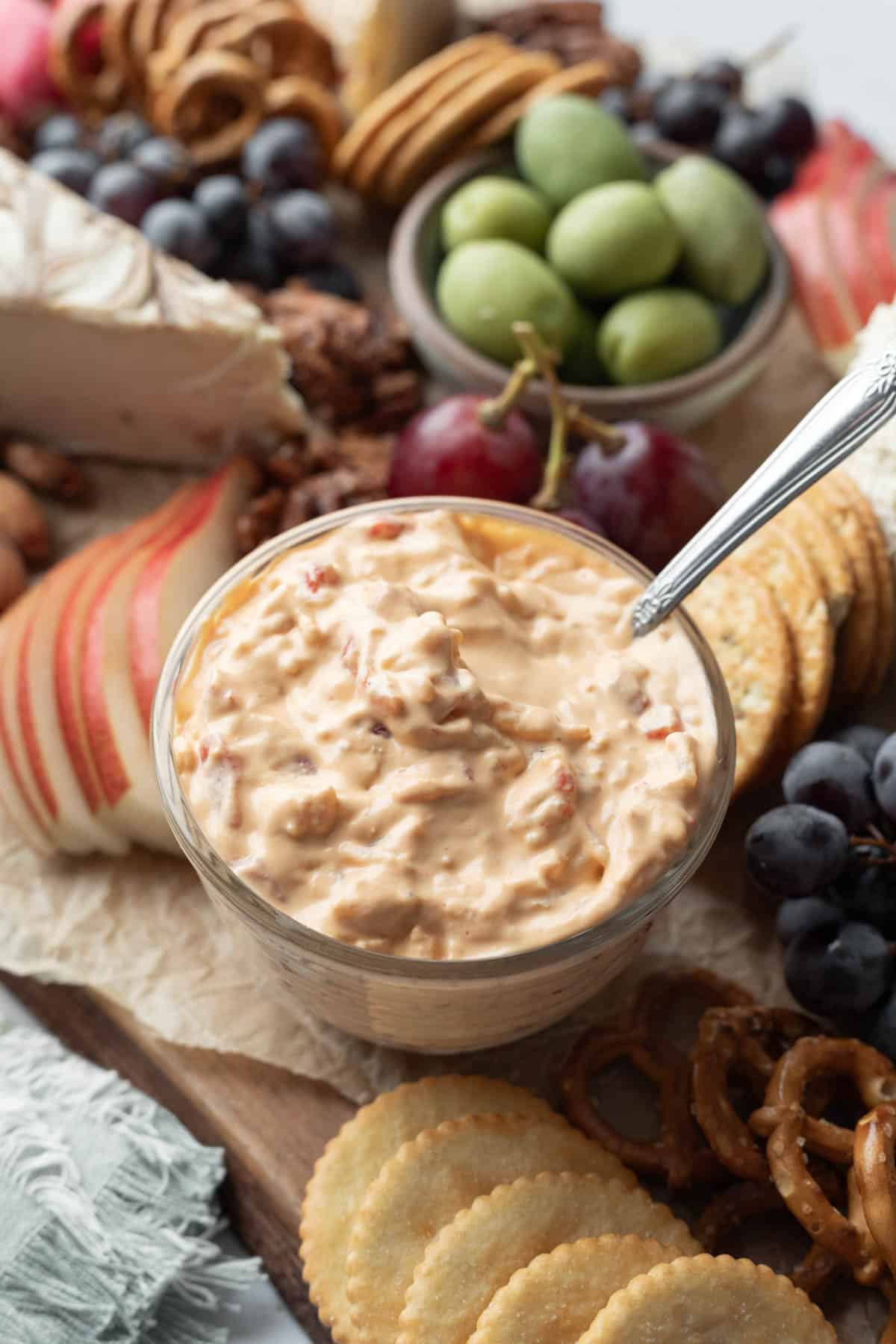 A vegan party platter with crackers, fruit, and pimento cheese dip.