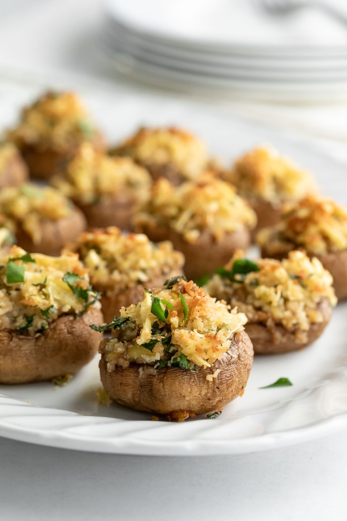 A brightly lit photo of vegan stuffed mushrooms on a white plate.
