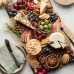 An elegant vegan cheese board with a variety of cheeses, fruits, snacks, and crackers for dipping.