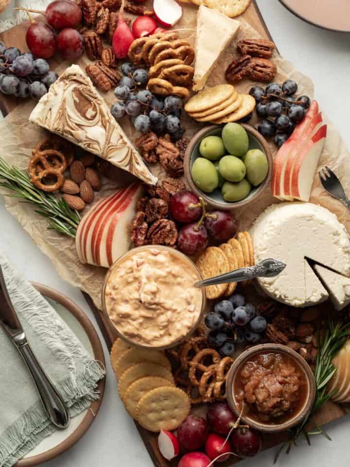 An elegant vegan cheese board with a variety of cheeses, fruits, snacks, and crackers for dipping.