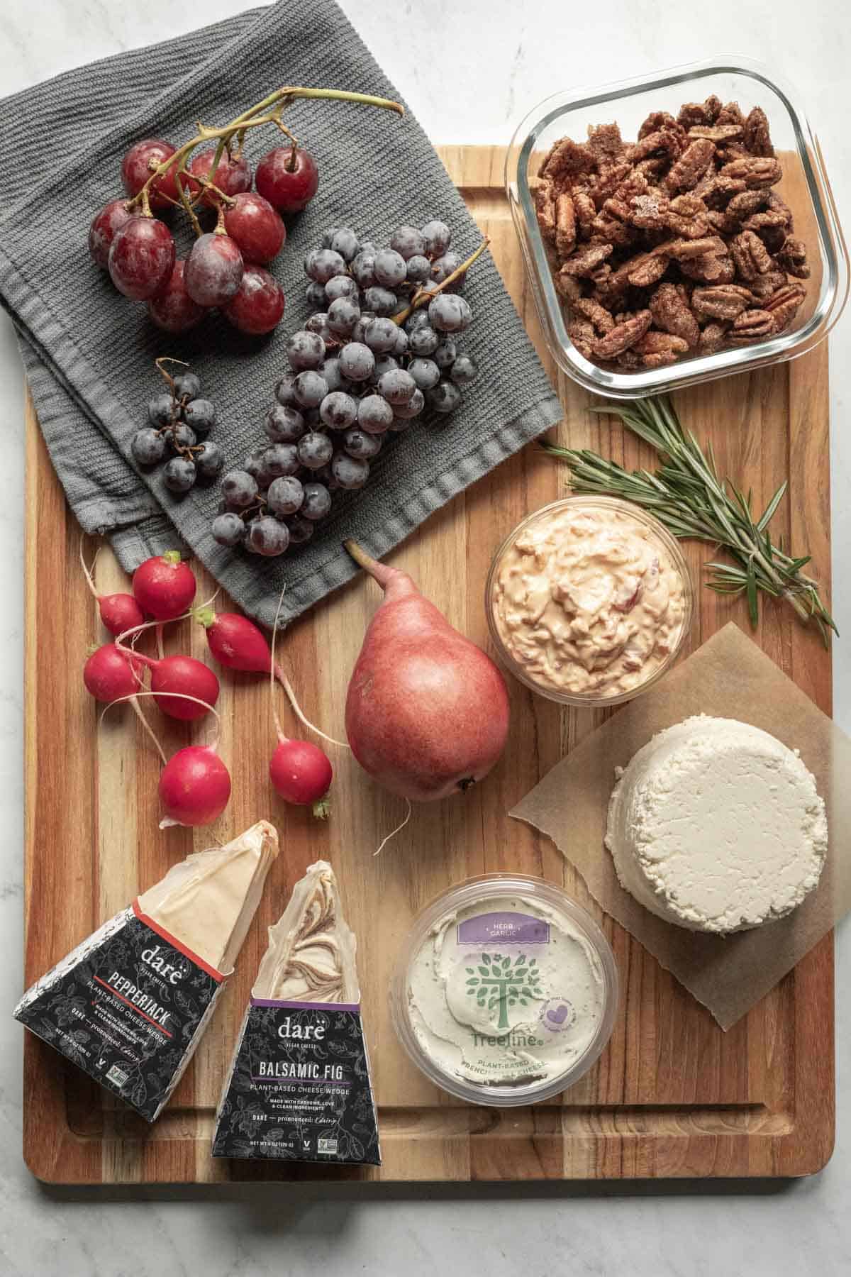 The ingredients used on our vegan cheese board laid out on a large wood cutting board.