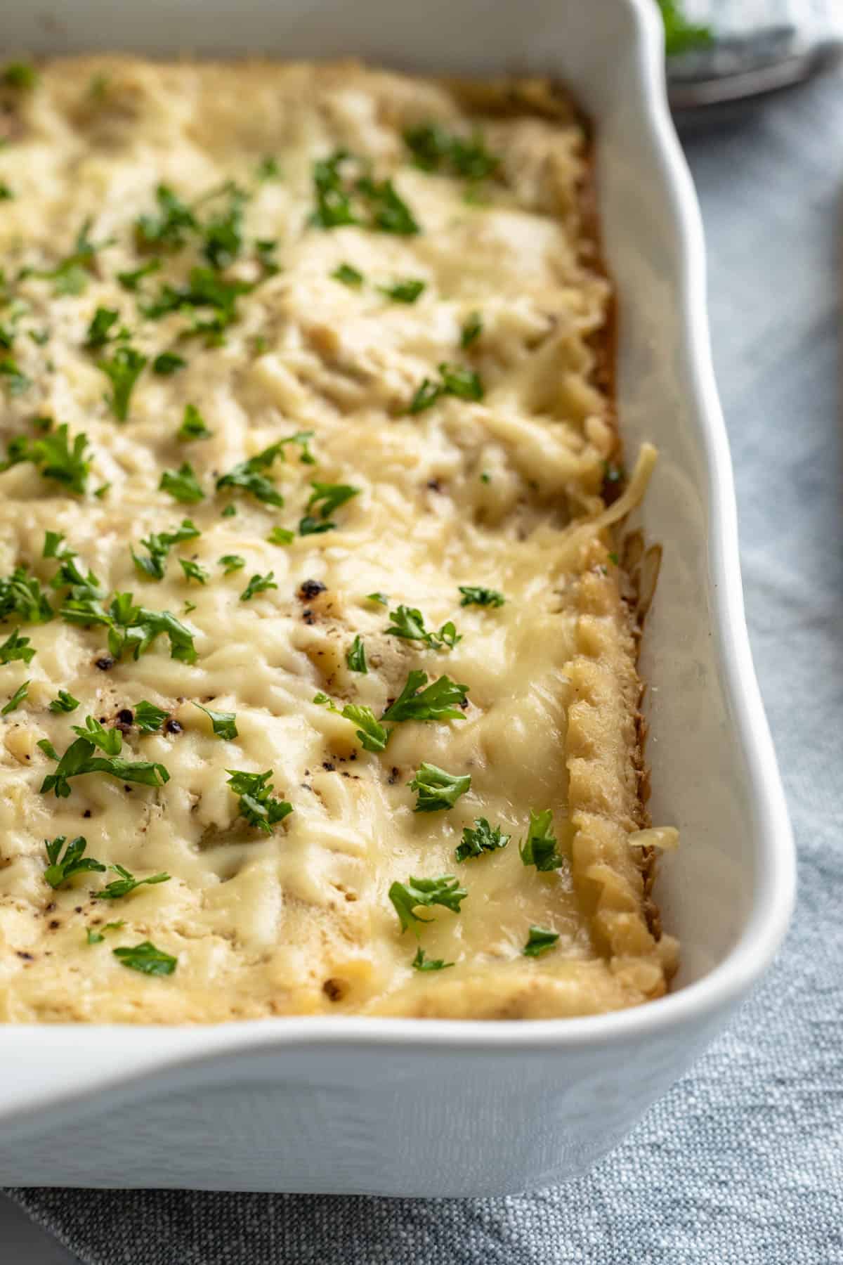 A pan of vegan white sauce lasagna resting on a table cloth.