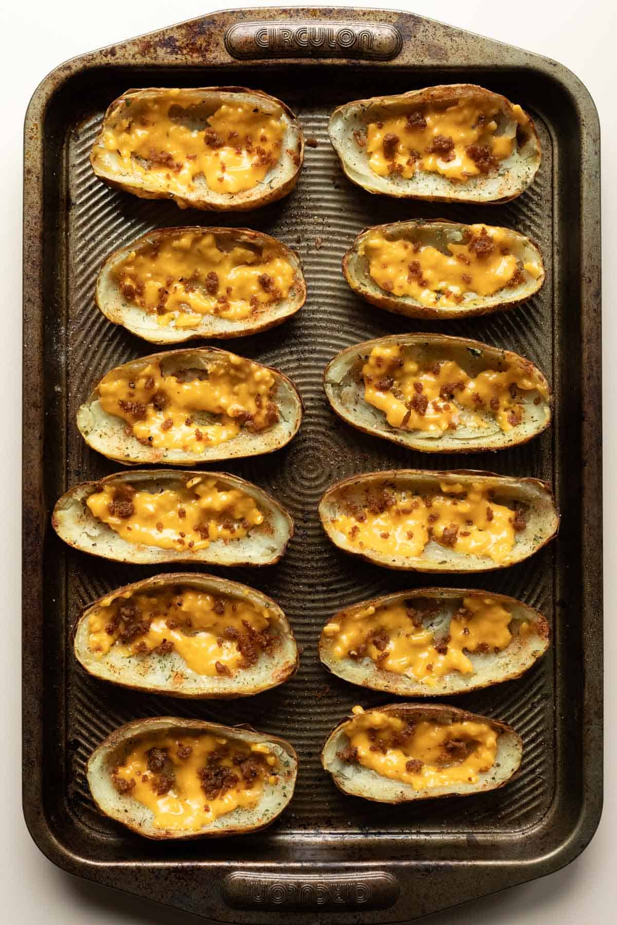 Filling the pre-baked potato skins with melted vegan cheddar cheese and tofu crumbles.