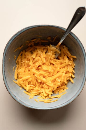 Melting vegan shredded cheddar in a bowl.