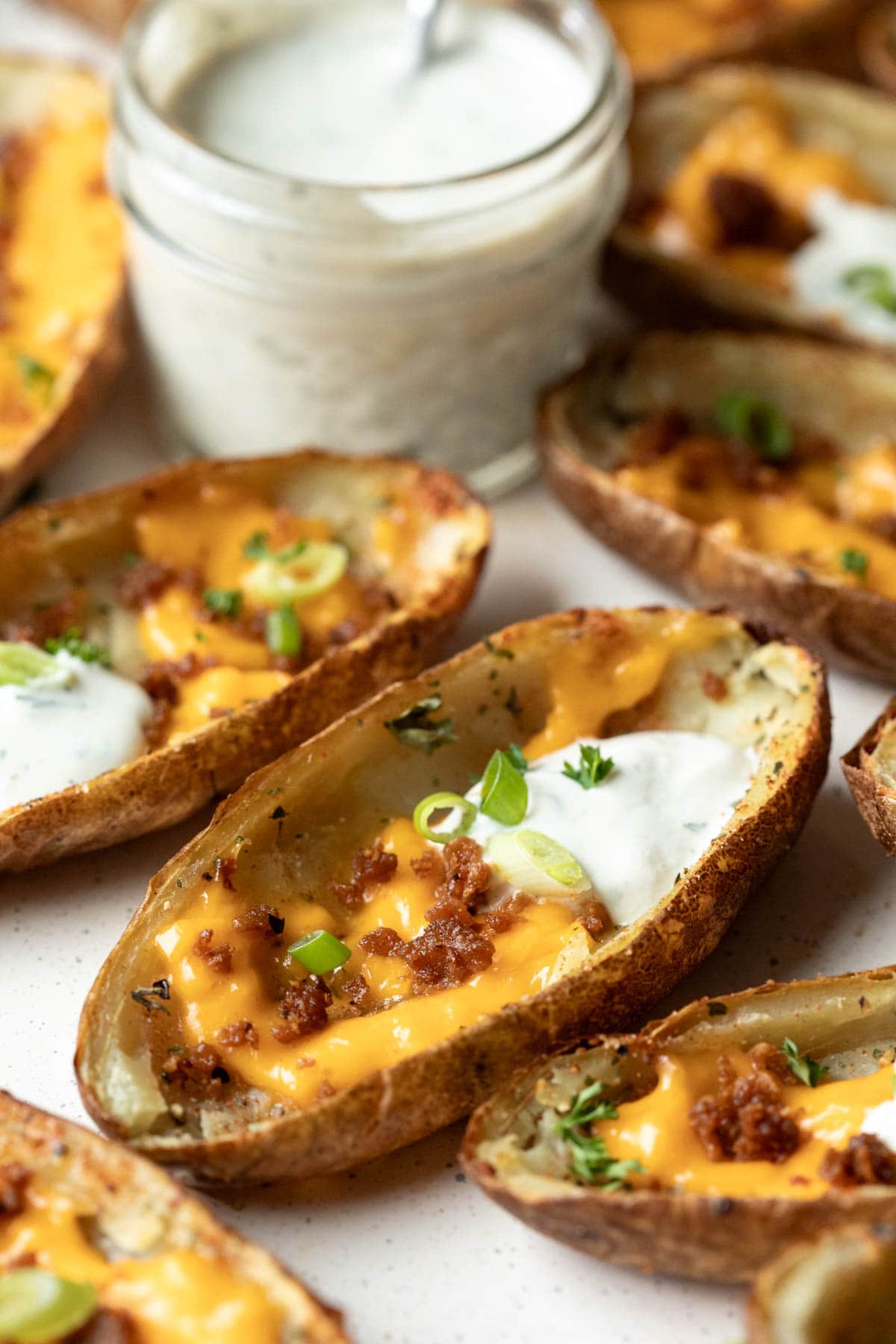 Close up of the texture of a potato skin topped with tofu bacon crumbles and melted vegan cheese.