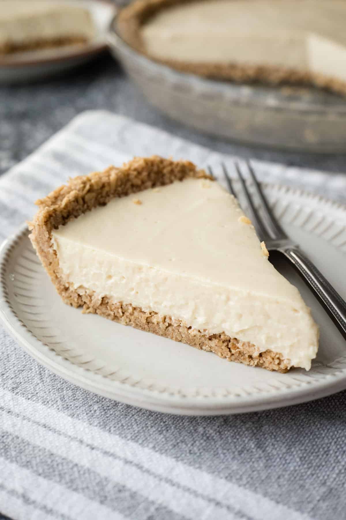 A slice of tofu cheesecake with oat crust on a small dessert plate.