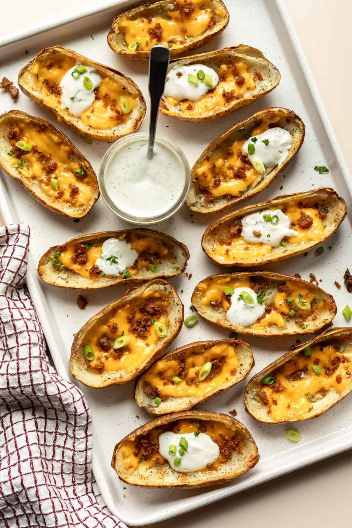 Baked potato skins on a tray, with some garnished with dairy-free sour cream.